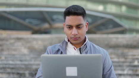 Konzentrierter-Junger-Mann,-Der-Einen-Laptop-Benutzt,-Während-Er-Draußen-Sitzt